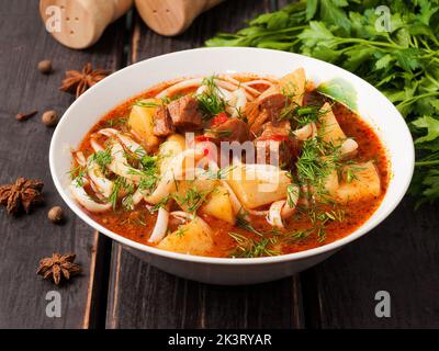 Schmackhafter Lagman mit Rindfleisch auf einem weißen Teller auf einem Holzboden Stockfoto