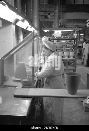 1950er Jahre, historisch, in der Fabrikhalle, eine Arbeiterin in in einem Overall und Haarnetz Herstellung von Töpferwaren bei Josiah Wedgwood & Sons Ltd. In Barlaston, Stoke-on-Trent, England, Großbritannien Stockfoto