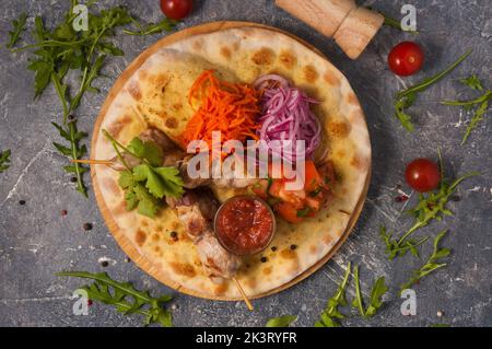 Schweinebab auf Pita-Brot mit Gemüse und Tomatensauce. Draufsicht Stockfoto