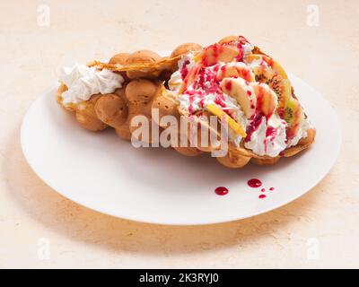 Leckere Waffeln aus Hongkong mit Obst und Schlagsahne auf einem weißen Teller Stockfoto