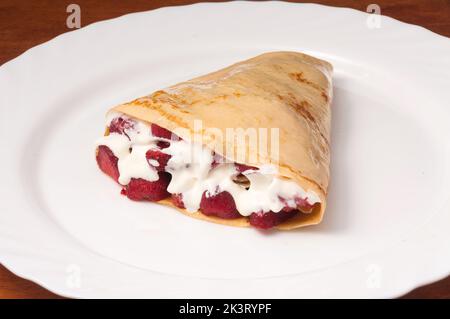 Pfannkuchen mit Erdbeeren und Rahm auf einem weißen Teller Stockfoto