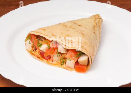 Leckere Crepe mit Tomaten und Huhn auf einem weißen Teller Stockfoto