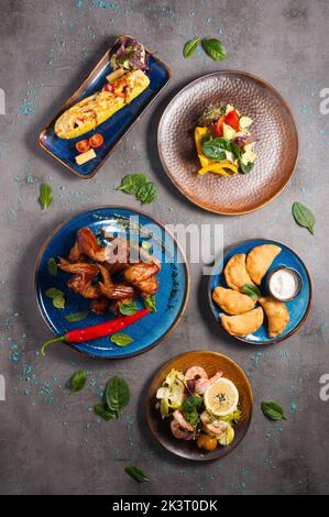 Set von leckeren heißen Vorspeisen: Chicken Wings, Garnelen, gefüllte Zucchini. Draufsicht Stockfoto