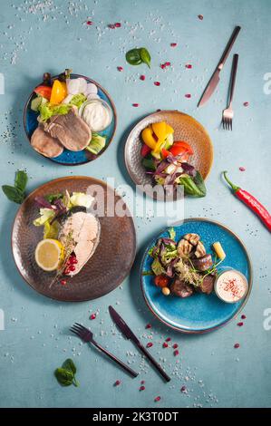 Leckere gesunde gedämpfte Speisen: Rinderzunge, Lachssteak, gedünstetes Gemüse, gedünstetes Rindfleisch Stockfoto