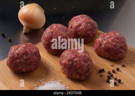 Leckere Fleischbällchen aus rohem Rindfleisch auf einem Holzbrett Stockfoto