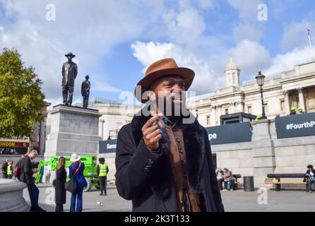 London, Großbritannien. 28. September 2022. Der Künstler Samson Kambalu genießt eine Zigarre neben seiner Skulptur 'Antelope', die als neuestes Kunstwerk für den vierten Sockel auf dem Trafalgar Square enthüllt wurde. Das Kunstwerk zeigt Statuen des panafrikanischen Predigers und Baptistenpredigers John Chilembwe und des europäischen Missionars John Chorley. Kredit: Vuk Valcic/Alamy Live Nachrichten Stockfoto