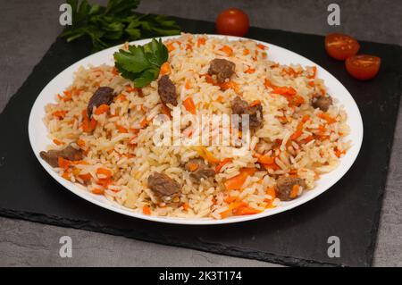 Schmackhafter usbekischer Pilaf mit Rindfleisch auf einem weißen Teller Stockfoto