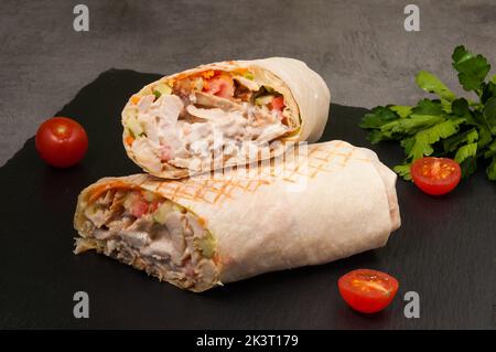 Leckere große Shawarma mit Gemüse und Huhn auf dunklem Hintergrund Stockfoto