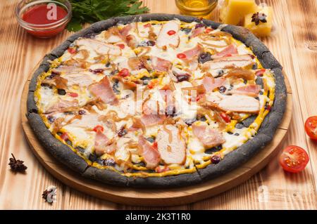 Leckere Pizza mit Hühnerspeck und Zwiebeln auf schwarzem Teig Stockfoto