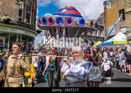 Ein großer Wagen einer fliegenden Untertasse wurde während einer Prozession am Mazey Day beim Golowan Festival in Penzance in Cornwall, Großbritannien, getragen. Stockfoto