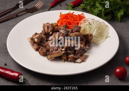 Leckere kleine Lammstücke auf dem Knochen mit Zwiebeln und Karotten Stockfoto