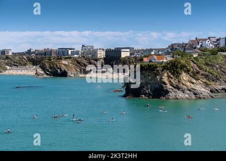 Urlauber auf Stand Up Paddleboards im Meer in Newquay Bay in Cornwall in England im Vereinigten Königreich. Stockfoto