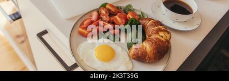 Hochwinkelansicht des Croissants in der Nähe von Ei und Kaffee in der Küche, Banner, Stockbild Stockfoto