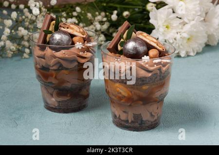 Süße Desserts in Plastikbechern mit Creme und Schokolade Stockfoto