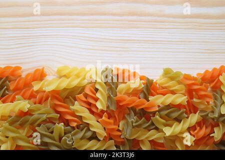 Haufen von Vegeroni spiralförmigen dreifarbigen Fusilli Pasta auf Holz Hintergrund Stockfoto