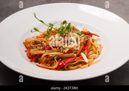 Leckere udon-Weizennudeln mit Gemüse Sesam und Microgreens Stockfoto