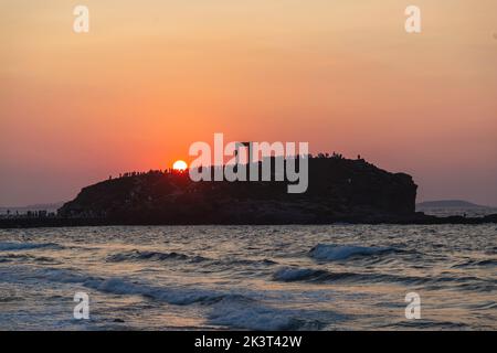 Insel Naxos, Sonnenuntergang über dem Tempel des Apollo, Kykladen Ziel Griechenland. Die Menschen bewundern den Sonnenuntergang von der Insel Palatia. Wellenmeer farbenfroher Himmel Stockfoto