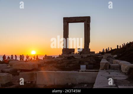 Insel Naxos, Sonnenuntergang über dem Tempel des Apollo, Kykladen Griechenland. Die Menschen genießen den Sonnenuntergang von der Insel Palatia. Stockfoto