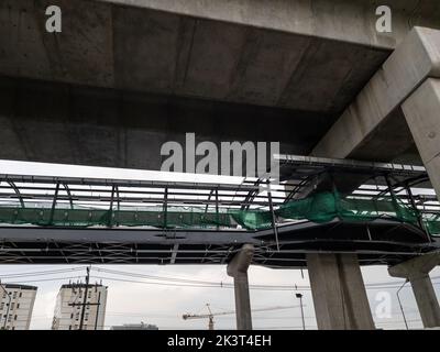 Die Baustelle der Fußgängerüberführung entlang der Betonsäule des U-Bahnhofs in der Stadt, Vorderansicht mit dem Kopierraum. Stockfoto
