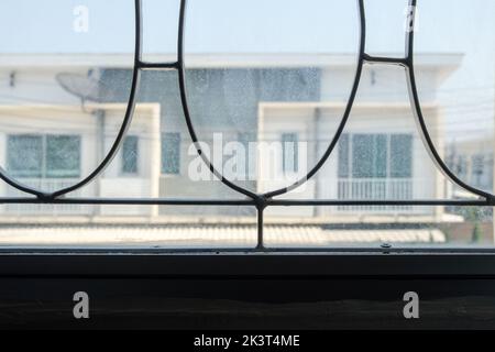 Nahaufnahme aus weiß lackiertem Schmiedeeisen durch das Buntfenster zum städtischen Dorf, Vorderansicht mit dem Kopierraum. Stockfoto