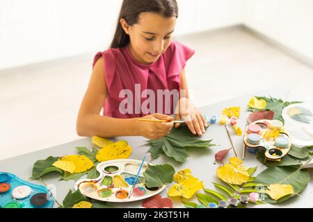 Herbstfertigkeit für Kinder. Tierfuchs aus Ahornblatt. Kinderkunst und Kreativität. Kunsthandwerk aus natürlichen Materialien. Mädchen zeichnet mit Farben. Stockfoto