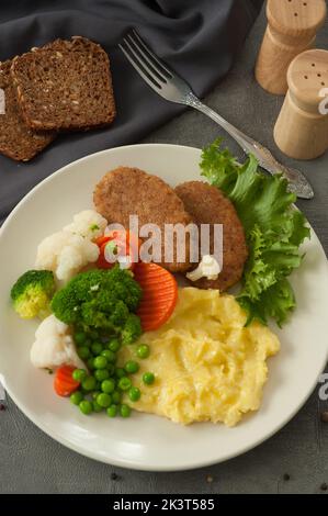 Leckere Kartoffelpüree mit Koteletts und gedämpftes Gemüse mit Getreidebrot Stockfoto