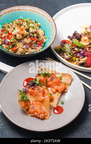 Leckere asiatische Speisen: Reis mit Garnelen, gebackenes Gemüse und Chips mit Lachs Stockfoto