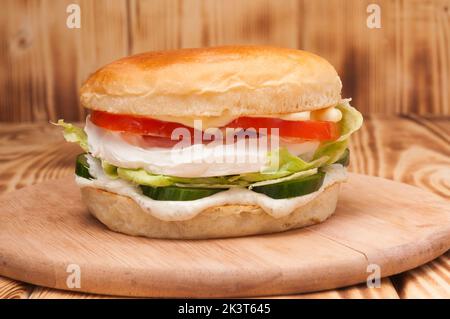 Schmackhafter vegetarischer Burger mit Frischkäse, Gurke und Tomaten Stockfoto