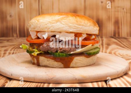 Leckerer Burger mit Rinderpastete, Gurken, Tomaten und Frischkäse Stockfoto