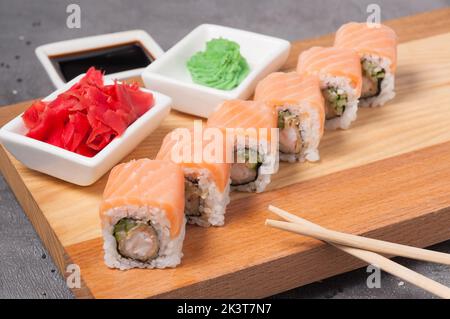 Leckere Sushi-Brötchen mit Tempura-Garnelen, Gurken und Lachs Stockfoto