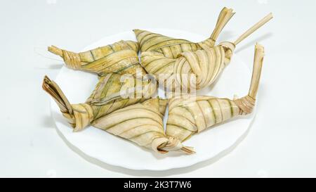 Berühmte malaiische klejeartige Reiskuchen, bekannt als „KETUPAT PALAS“ auf weißem Hintergrund. Ein selektives Fokusfoto von 'KETUPAT PALAS'. Stockfoto