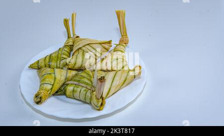 Berühmte malaiische klejeartige Reiskuchen, bekannt als „KETUPAT PALAS“ auf weißem Hintergrund. Ein selektives Fokusfoto von 'KETUPAT PALAS'. Stockfoto