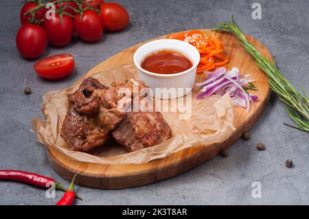 Leckerer Schweinehals-Kebab mit Tomatensauce auf einem Holzbrett Stockfoto