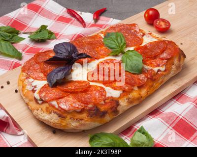 Leckere Pepperoni-Pizza auf römischem Teig auf einem Holzbrett Stockfoto