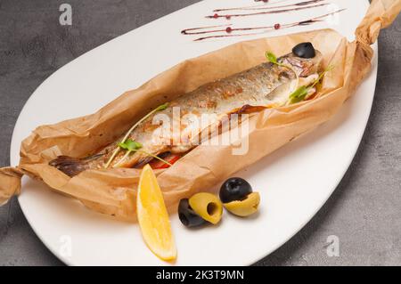 Leckere Forelle gefüllt mit Gemüse, gebacken in Pergamentpapier Stockfoto