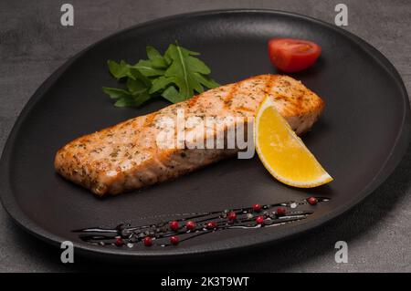 Leckeres gegrilltes Lachssteak auf einem dunklen Teller Stockfoto