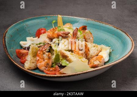 Leckere caesar mit Garnelen, Croutons, Parmesan und Wachtelei auf einem blauen Teller Stockfoto