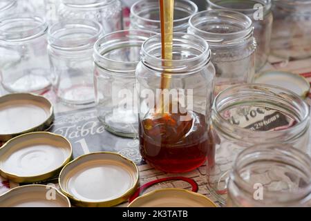 Die Füllung der Glasgefäße des Honigs auf dem Tisch Stockfoto