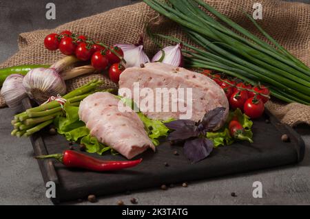 Schmackhaftes Wurstprodukt - gepresstes Fleisch mit frischem Gemüse dekoriert Stockfoto