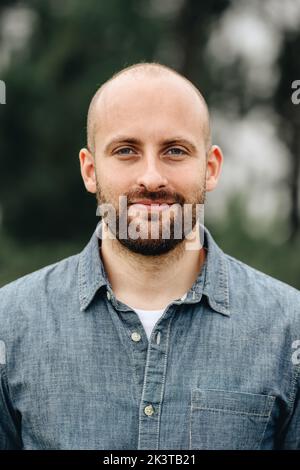 Porträt eines gutaussehenden bärtigen Glatzkahls in legerer Kleidung, der selbstbewusst die Kamera anschaut Stockfoto