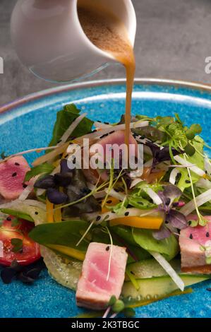 Leckerer Salat mit Gemüse, gebratenem Thunfisch und Honig-Senf-Sauce. Nahaufnahme Stockfoto