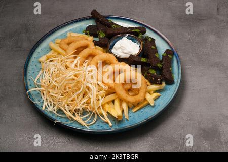 Leckere Biersnacks: Zwiebelringe, Knoblauchcroutons, Käse mit saurer Sahnesauce Stockfoto