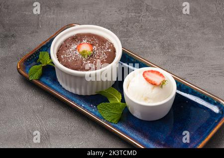 Süßes Schokoladenfondant mit Eiscreme, verziert mit Minze und Erdbeeren Stockfoto