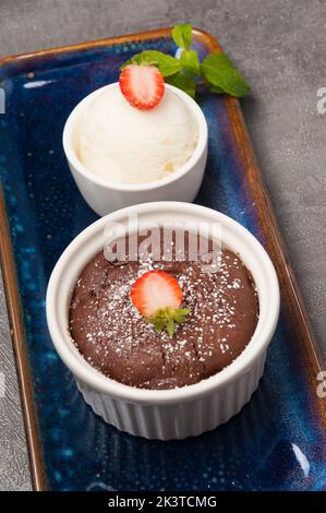 Süßes Schokoladenfondant mit Eiscreme, verziert mit Minze und Erdbeeren Stockfoto