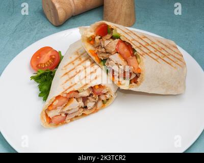 Leckeres Shawarma mit Huhn und Gemüse auf blauem Hintergrund Stockfoto