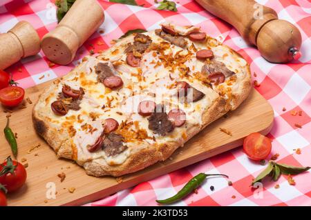 Leckere Pizza auf römischem Teig mit bayerischen Würstchen, Huhn und Rind Stockfoto