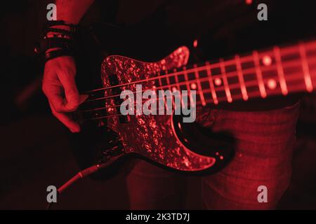 Nahaufnahme eines anonymen Mannes, der in rotem Licht Gitarre spielt Stockfoto