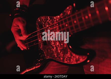 Nahaufnahme eines anonymen Mannes, der in rotem Licht Gitarre spielt Stockfoto