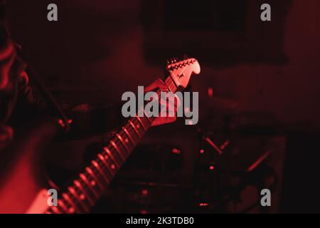 Nahaufnahme eines anonymen Mannes, der in rotem Licht Gitarre spielt Stockfoto