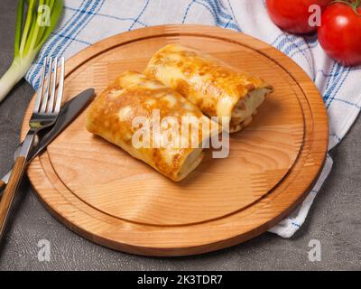 Leckere Pfannkuchen mit Füllung auf einem Holzbrett Stockfoto